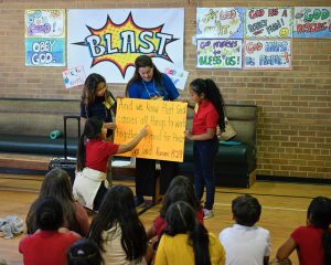 BLAST Students read a Bible verse from a sign held by a volunteer during one of their sessions.